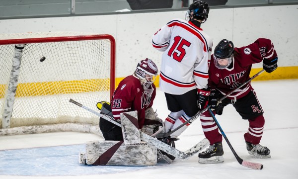 St. George's freshman Julian Frias (#15) deflects the puck past Roxbury Latin senior goaltender Mikey Jones in the first period of the Dragons' 3-1 ro